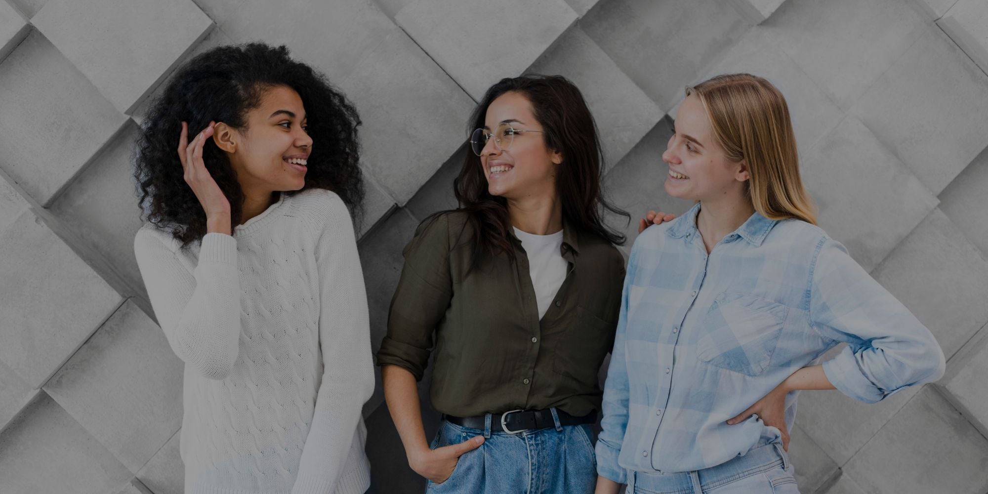 Three women standing together against a textured wall.